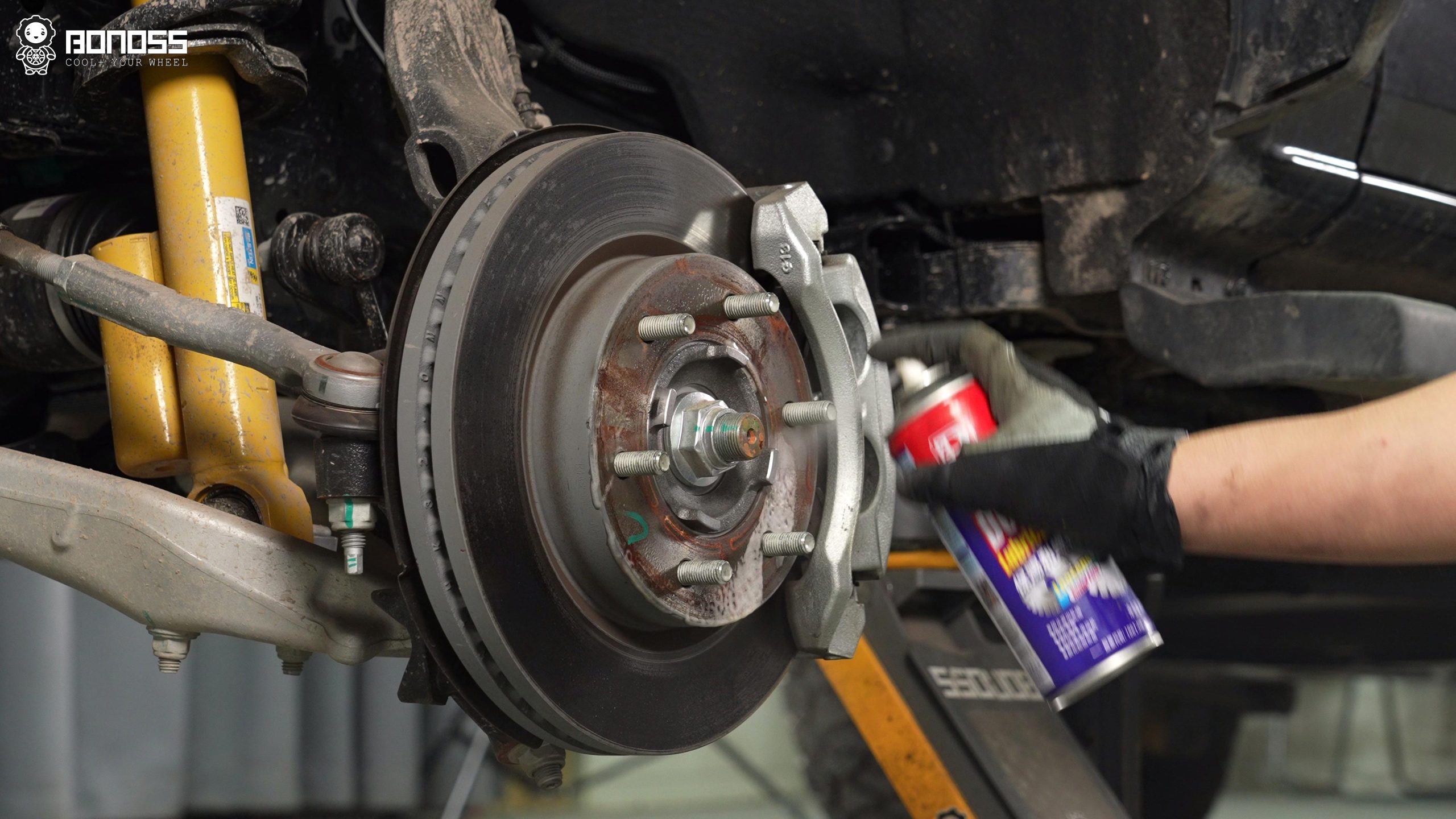 BONOSS Forged Active Cooling Hubcentric Bronco Wheel Spacers Installation Steps (2) A man is spraying degreaser on a wheel hub to clean it